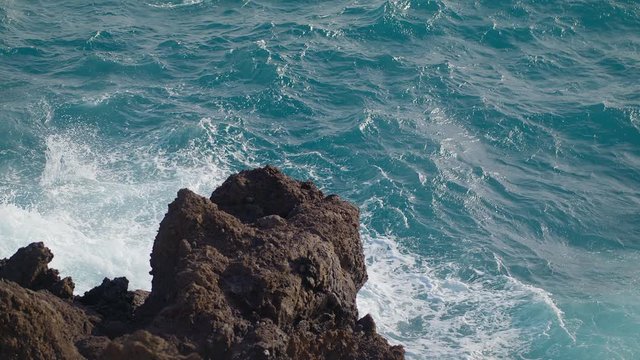 Storm in the Pacific Ocean Waves Break the rocks of the shore Water turns into Foam Droplets and Splashes Clear Blue water of the Sea. Gale Tide is playing with the Sun shot slow motion URSA 4.6K