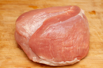 fresh piece of pork ham meat on a cutting board with a knife