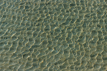 Shallow of sea on sandy beach close up. Beautiful soft waves, marine background.