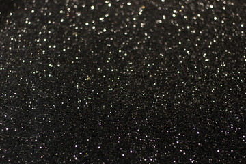 Black surface with white glare and bokeh. Black and white texture background. Blurred edges.