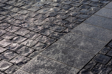 Wet dark basalt paving in the evening light.