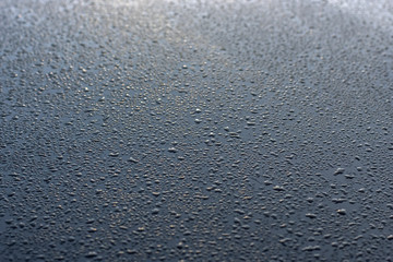 Water droplets on blue metal surface.
