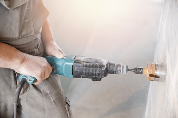 Builder worker pneumatic hammer drills hole in concrete brick wall with diamond crown for electric...
