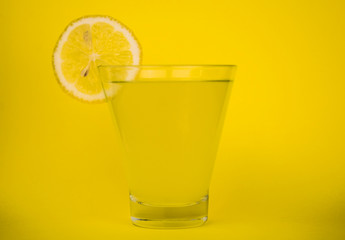  A glass of fresh lemon juice on a yellow background.