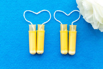 women's tampons with a rose flower on a blue background. The concept of women's health.