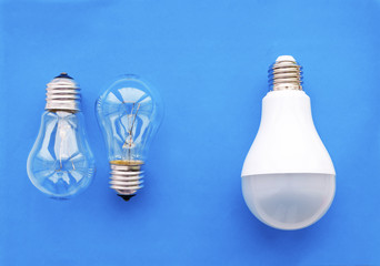 Energy-saving lamp with incandescent lamps in a row on a blue background. The concept of saving energy.