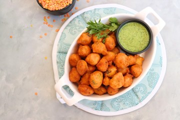 Moong dal ke pakode, ram laddoo, bhajias, Moongode or fritters. served with green mint and coriander chutney. Served over light background. Selective focus. with copy space.