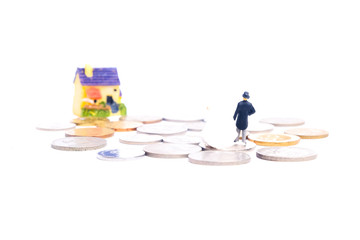 Selective focus of wedding couple miniature with coin and house miniature insight. Newly wedding couple house ownership campaign concept.