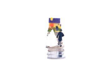 Selective focus of wedding couple miniature with coin and house miniature insight. Newly wedding couple house ownership campaign concept.