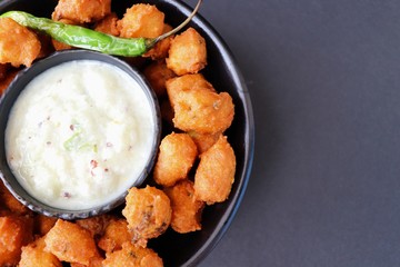 Moong dal ke pakode, ram laddoo, bhajias, Moongode or fritters. served with green mint and coriander chutney. Served over light background. Selective focus. with copy space.