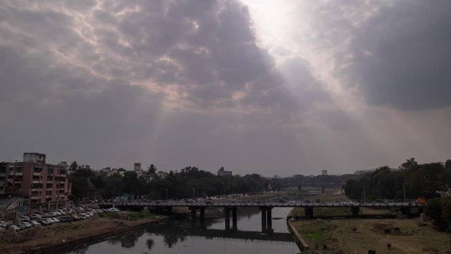 Timelapse of light pillars shining through clouds onto a busy bridge