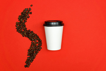 Top view of white paper dispocable coffee cup on red backgeound with coffee beans.