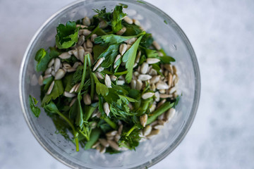 Fresh green pesto with sunflower seeds, dill, parsley, mint in glass blender jar.