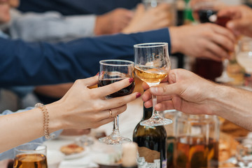 hands of a group of friends clinking glasses of wine and toasting