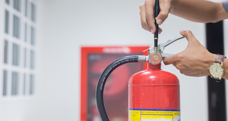 Technician checking red fire extinguishers available in fire emergencies,safety concept.