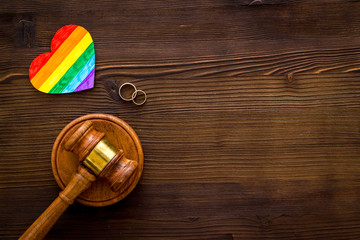 LGBT divorce. Rainbow heart near rings and judge gavel on wooden background top-down copy space