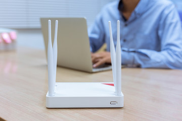 Wireless router and man using a laptop in office.