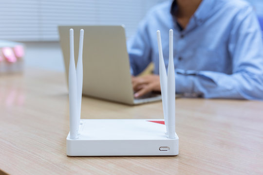 Wireless Router And Man Using A Laptop In Office.