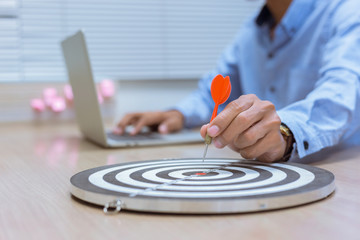 Businessman holding a darts aiming at the target center business goal concept