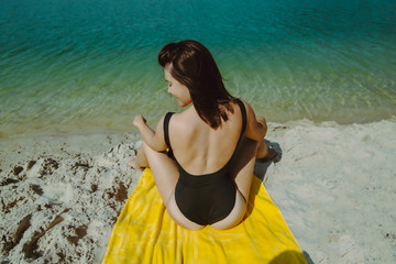 woman with sexy ass sitting on yellow blanket in swimsuit at sand beach