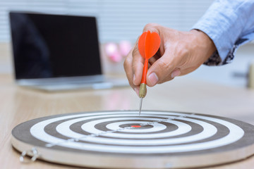 Businessman holding a darts aiming at the target center business goal concept