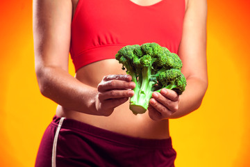 Naklejka na ściany i meble Woman holding broccoli. People, fitness and healthcare concept