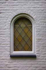 yellow green arched window in white brick wall