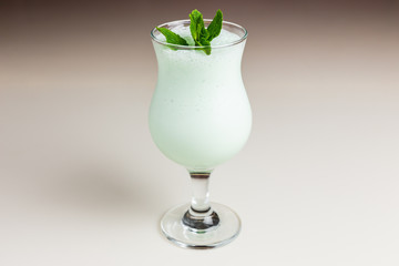 A bright green milkshake in a hurricane glass garnished with a mint sprig