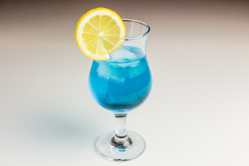 A blue lagoon cocktail in a hurricane glass garnished with a lemon wheel