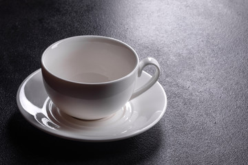 Preparation of aromatic morning coffee. Empty white coffee cup on a dark table