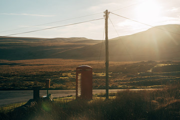 red telephone box in field with electro pole