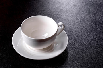 Preparation of aromatic morning coffee. Empty white coffee cup on a dark table