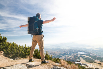 Rear view of man with backpack hiking in mountains in summer.