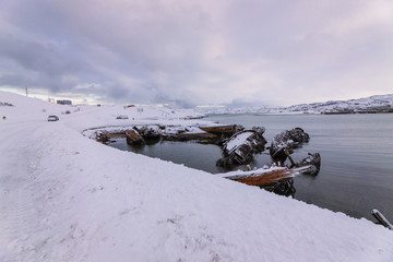 Graveyard of ships in the old fishing village on the shore of the Barents sea, the Kola Peninsula, Teriberka, Russia
