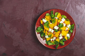 Healthy salad with persimmon, doucette (lambs-lettuce, cornsalad, feld salad) and feta cheese. Fitness food, superfoods vitamin persimmon salad. Top view, flat lay, copy space.