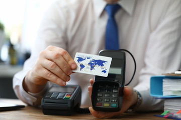 Man shows credit card offers terminal choose. Installation finance terminals, supply communications and initial consultations for staff. POS-terminal communications are provided by bank