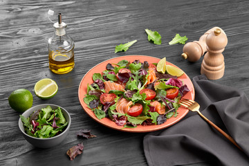Salmon salad, cherry tomatoes, spinach, radicio, lollo. Home made vegetarian salmon salad. Seafood tasty concept. Mix leaves greens with salmon fish in plate on dark wood background.