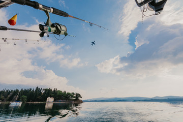 fishing rods held in fishing rod holders, attached to a back of a boat - Image