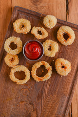 Fototapeta premium Golden crispy onion rings coated with breadcrumbs and deep fried. Fast food, junk food concept.