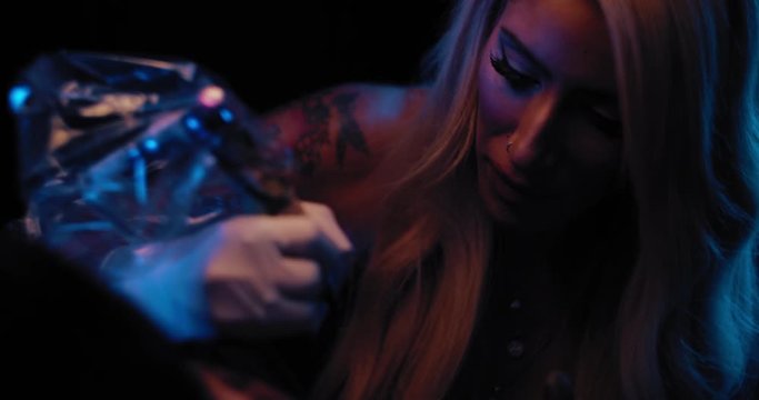 Close up of a young female tattoo master tattooing in her studio. BMPCC 4K