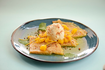 Vanilla ice cream dessert with pineapple fruit and raw mint leaves. Sweet delicious ice cream cold dessert on blue plate