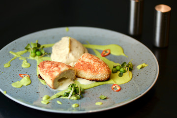 Cordon bleu chicken cutlet. Keiv cutlet with gravy and sauce served on a blue plate on dark rustic wooden table.