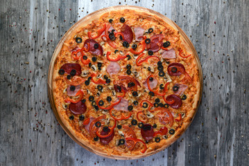 Flat lay photograph of tasty italian pizza on rustic wood. Pepperoni, cheese and peppers. Delicious food.