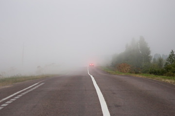 The car on the road in thick mist. Danger driving