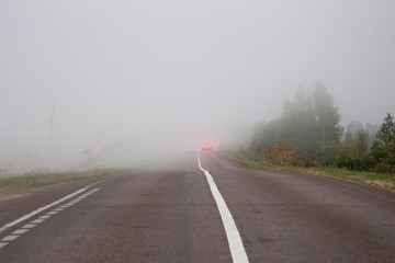 Fototapeta na wymiar The car on the road in thick mist. Danger driving