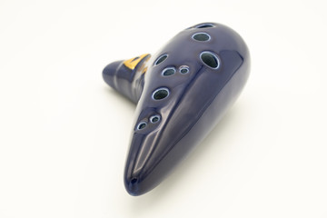 A dark blue ocarina in front of white background