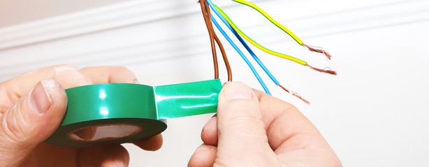 Man is holding adhesive tape in his hands.  Electrical insulator for light bulb. Maintenance repair...
