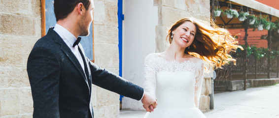 Wedding couple runs in the old city. Blue vintage doors and cafe in ancient sunny town on...