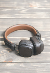 Fototapeta na wymiar Brown leather headphones on vintage wooden background. Modern music concept.