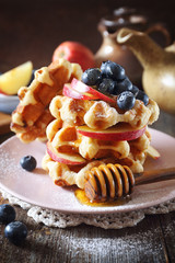 Belgian waffles with blueberries, apples and honey for breakfast